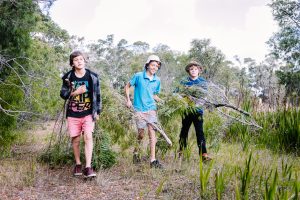 Sol Garland, Ali White and Dalton Marsh collect branches to build the Mia-Mia.